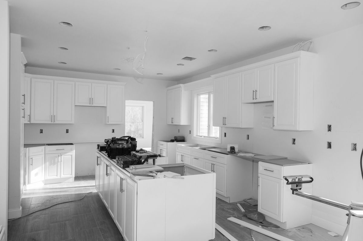 Kitchen mid-renovation with white cabinetry and tools