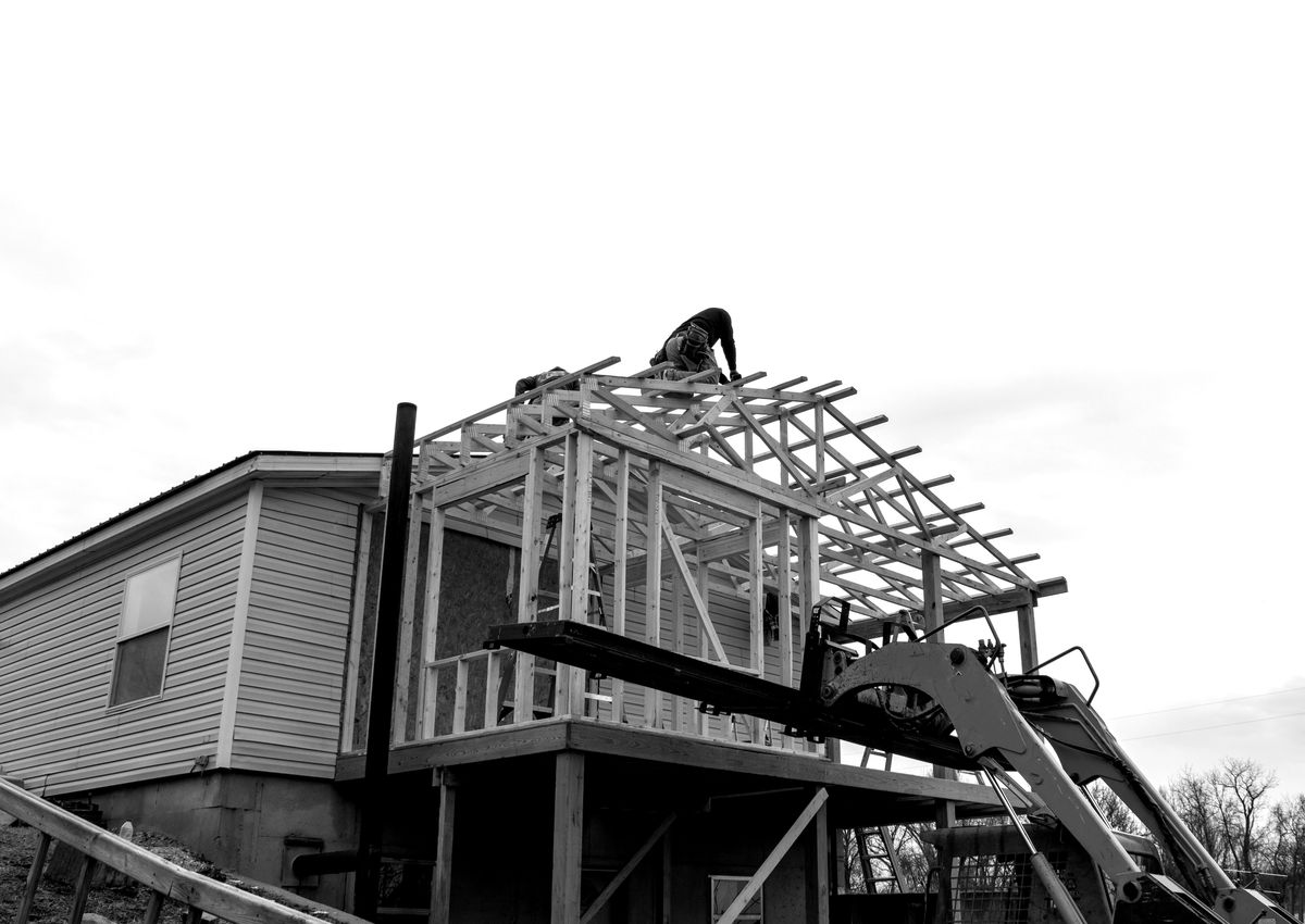 House framing under construction with contractor on roof