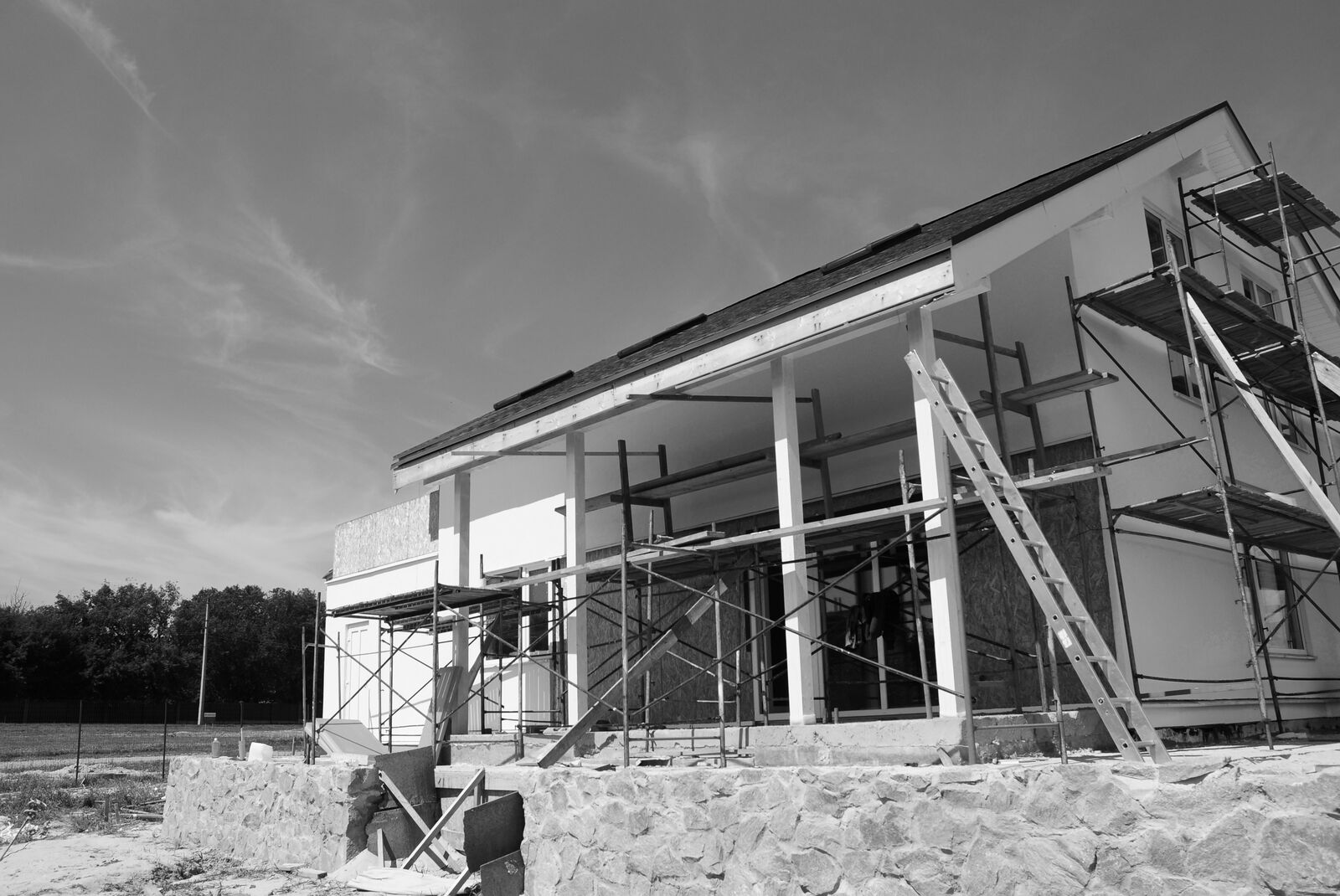 A two-story home in mid-build, scaffolding still up against the framing under an open sky.